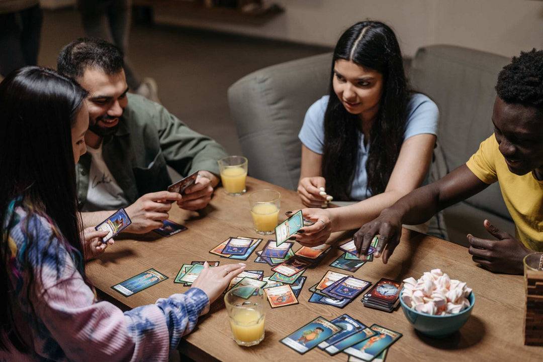 Group of friends playing a card game on a table while drinking