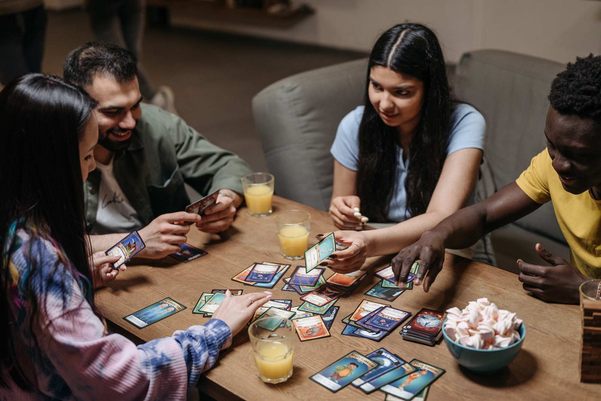 Group of friends playing a card game on a table while drinking